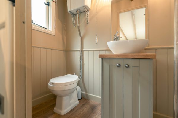 A small bathroom inside a shepherds hut with toilet, basin and shower