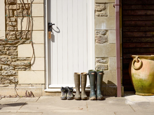 set of walking boots and wellies outside a holiday cottage door